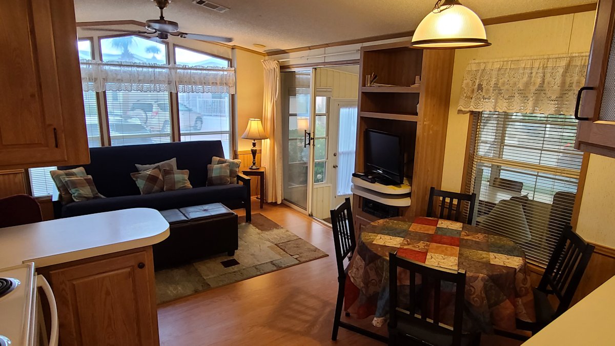 Living room with futon, reclining chair, ottoman seating, and flat screen TV.